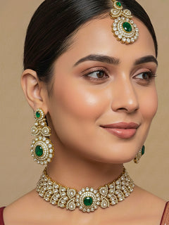 Close-up of a woman wearing an ornate traditional Green Diamond gold Polish Choker jewellery set and earrings and maangtikka with American Diamond and Green Colored Stones. A woman wearing a luxury American diamond necklace set styled beautifully for a wedding guest look in India. Mehendi function outfit styled with a lightweight American Diamond Necklace.