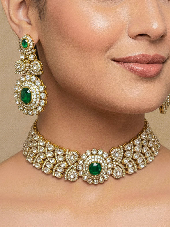Close-up of a woman wearing an ornate traditional Green Diamond gold Polish Choker jewellery set and earrings and maangtikka with American Diamond and Green Colored Stones. A woman wearing a luxury American diamond necklace set styled beautifully for a wedding guest look in India. Mehendi function outfit styled with a lightweight American Diamond Necklace.