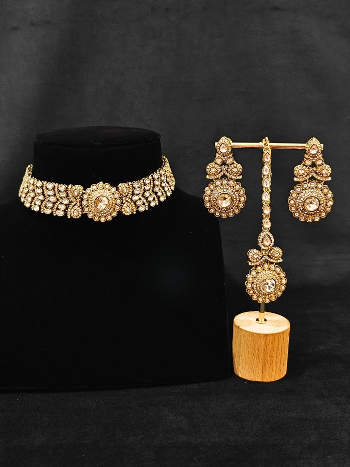 Close-up of an ornate traditional White Diamond gold Polish Choker jewellery set and earrings and maangtikka with American Diamond. A luxury American diamond necklace set styled beautifully for a wedding guest look in India. Mehendi function outfit styled with a lightweight American Diamond Necklace.