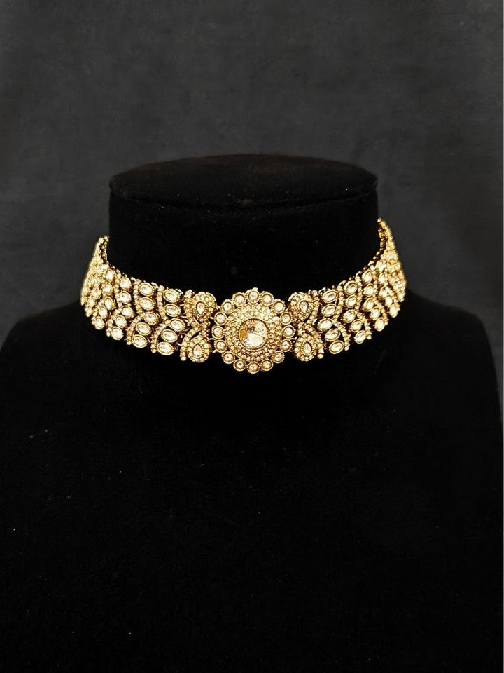 Close-up of an ornate traditional White Diamond gold Polish Choker jewellery set and earrings and maangtikka with American Diamond. A luxury American diamond necklace set styled beautifully for a wedding guest look in India. Mehendi function outfit styled with a lightweight American Diamond Necklace.