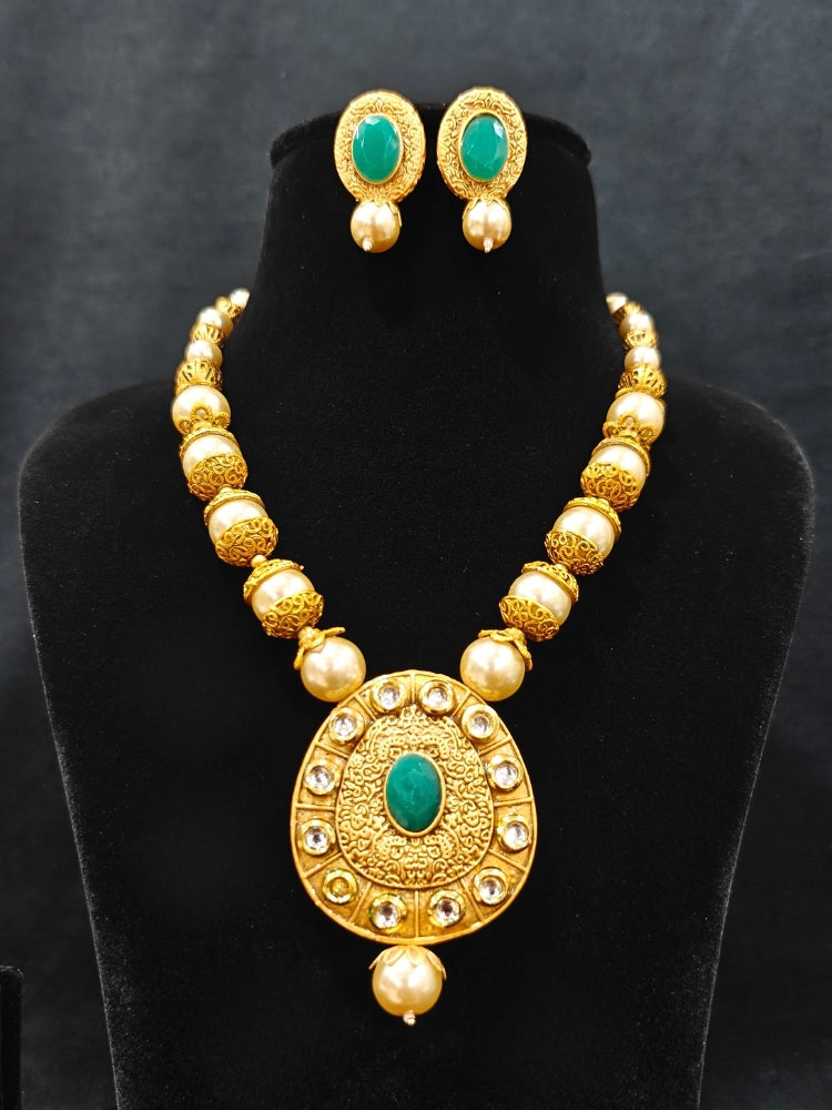 Close-up of an ornate traditional (Gold Polish) Long jewellery set and earrings with Kundan, Colored Stones and Pearls. Wedding guest look featuring a Long imitation Pearl jewelry set. Traditional Indian wedding look featuring a bridal Long set.