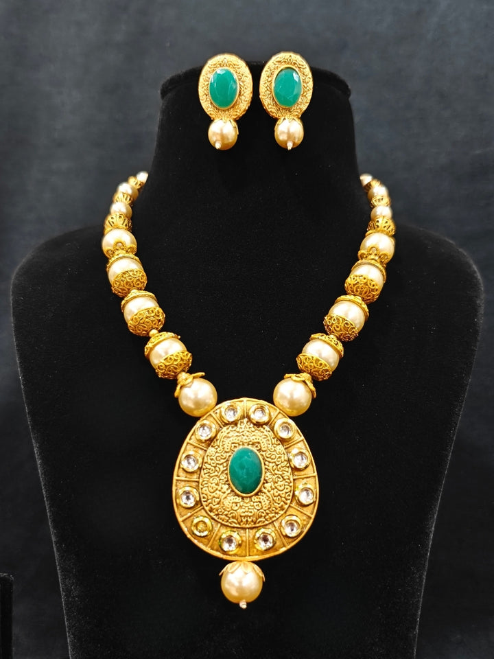 Close-up of an ornate traditional (Gold Polish) Long jewellery set and earrings with Kundan, Colored Stones and Pearls. Wedding guest look featuring a Long imitation Pearl jewelry set. Traditional Indian wedding look featuring a bridal Long set.