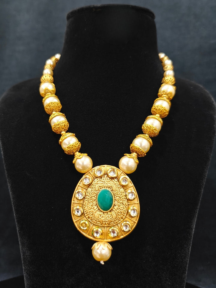 Close-up of an ornate traditional (Gold Polish) Long jewellery set and earrings with Kundan, Colored Stones and Pearls. Wedding guest look featuring a Long imitation Pearl jewelry set. Traditional Indian wedding look featuring a bridal Long set.