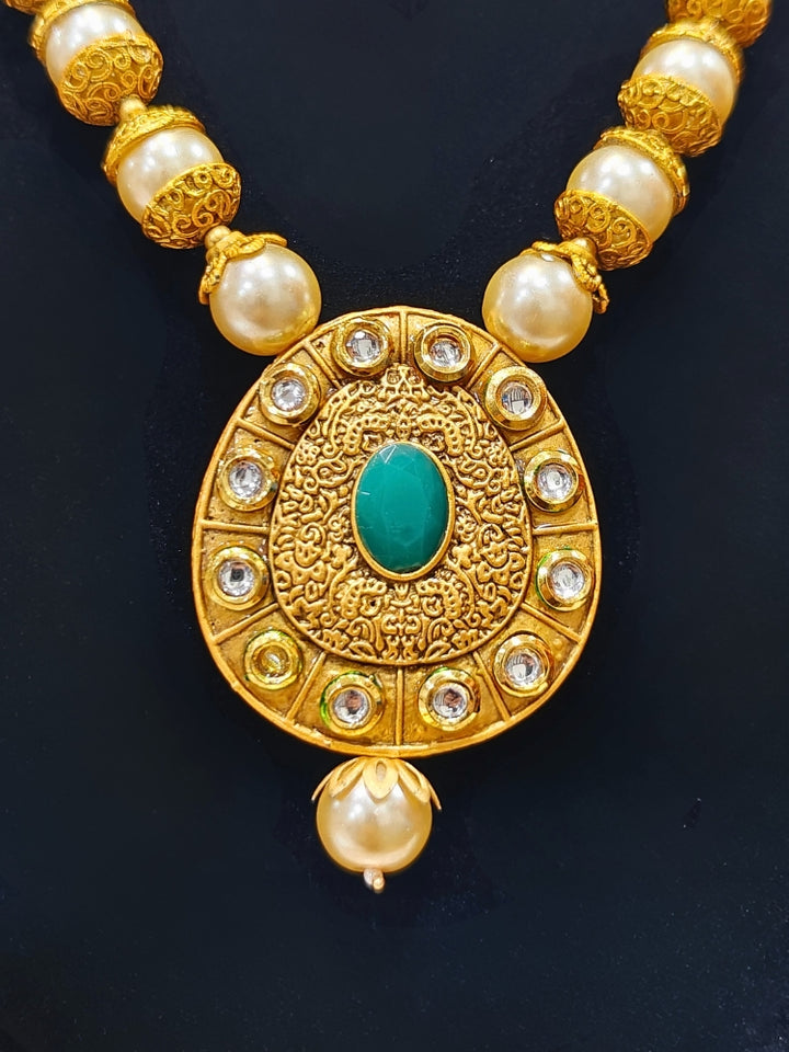 Close-up of an ornate traditional (Gold Polish) Long jewellery set and earrings with Kundan, Colored Stones and Pearls. Wedding guest look featuring a Long imitation Pearl jewelry set. Traditional Indian wedding look featuring a bridal Long set.
