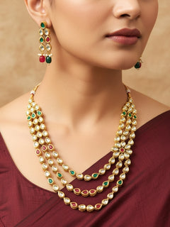 Close-up of a woman wearing an ornate traditional (Gold Polish) Red & Green Kundan jewellery set and earrings with Kundan and Red & Green Colored Stones. Mehendi ceremony look completed with a handcrafted Kundan jewelry set. Royal bridal look featuring a traditional Kundan necklace set.