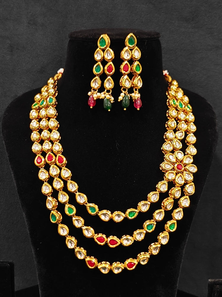 Close-up of an ornate traditional (Gold Polish) Red & Green Kundan jewellery set and earrings with Kundan and Red & Green Colored Stones. Mehendi ceremony look completed with a handcrafted Kundan jewelry set. Royal bridal look featuring a traditional Kundan necklace set.