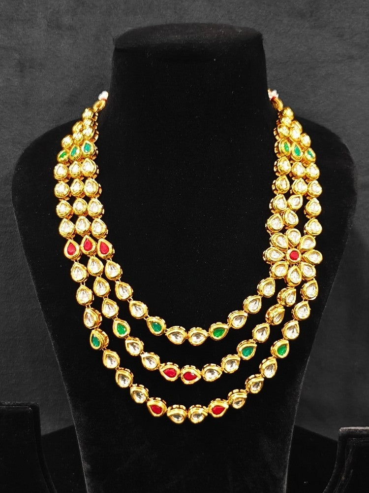 Close-up of an ornate traditional (Gold Polish) Red & Green Kundan jewellery set and earrings with Kundan and Red & Green Colored Stones. Mehendi ceremony look completed with a handcrafted Kundan jewelry set. Royal bridal look featuring a traditional Kundan necklace set.