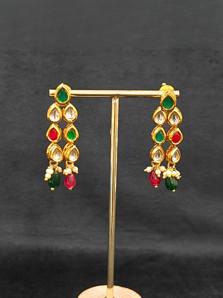 Close-up of an ornate traditional (Gold Polish) Red & Green Kundan jewellery set and earrings with Kundan and Red & Green Colored Stones. Mehendi ceremony look completed with a handcrafted Kundan jewelry set. Royal bridal look featuring a traditional Kundan necklace set.