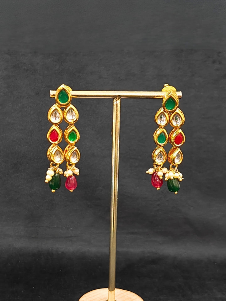 Close-up of an ornate traditional (Gold Polish) Red & Green Kundan jewellery set and earrings with Kundan and Red & Green Colored Stones. Mehendi ceremony look completed with a handcrafted Kundan jewelry set. Royal bridal look featuring a traditional Kundan necklace set.