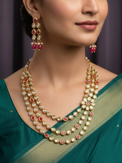 Close-up of a woman wearing an ornate traditional (Gold Polish) Red Kundan jewellery set and earrings with Kundan and Red Colored Stones. Mehendi ceremony look completed with a handcrafted Kundan jewelry set. Royal bridal look featuring a traditional Kundan necklace set.