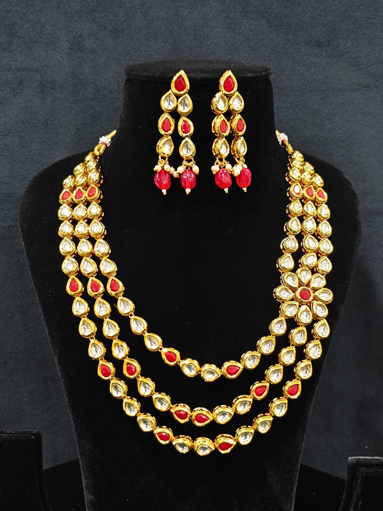 Close-up of an ornate traditional (Gold Polish) Red Kundan jewellery set and earrings with Kundan and Red Colored Stones. Mehendi ceremony look completed with a handcrafted Kundan jewelry set. Royal bridal look featuring a traditional Kundan necklace set.