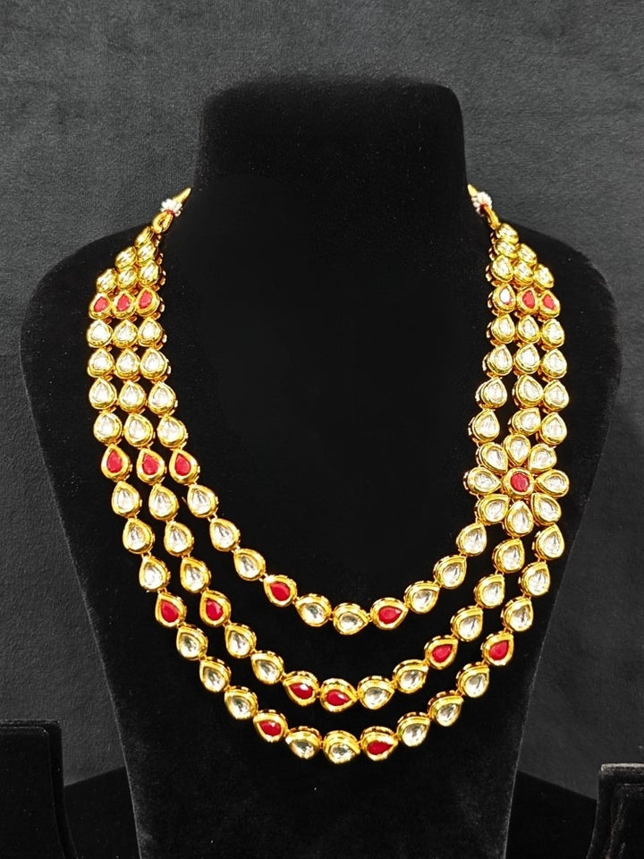 Close-up of an ornate traditional (Gold Polish) Red Kundan jewellery set and earrings with Kundan and Red Colored Stones. Mehendi ceremony look completed with a handcrafted Kundan jewelry set. Royal bridal look featuring a traditional Kundan necklace set.