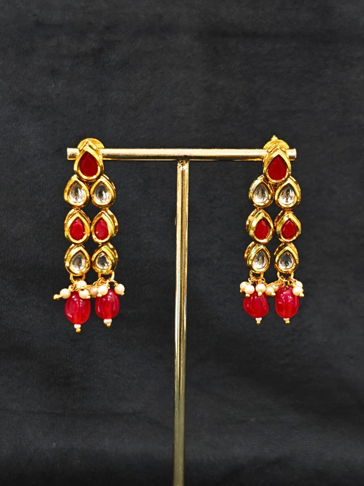 Close-up of an ornate traditional (Gold Polish) Red Kundan jewellery set and earrings with Kundan and Red Colored Stones. Mehendi ceremony look completed with a handcrafted Kundan jewelry set. Royal bridal look featuring a traditional Kundan necklace set.