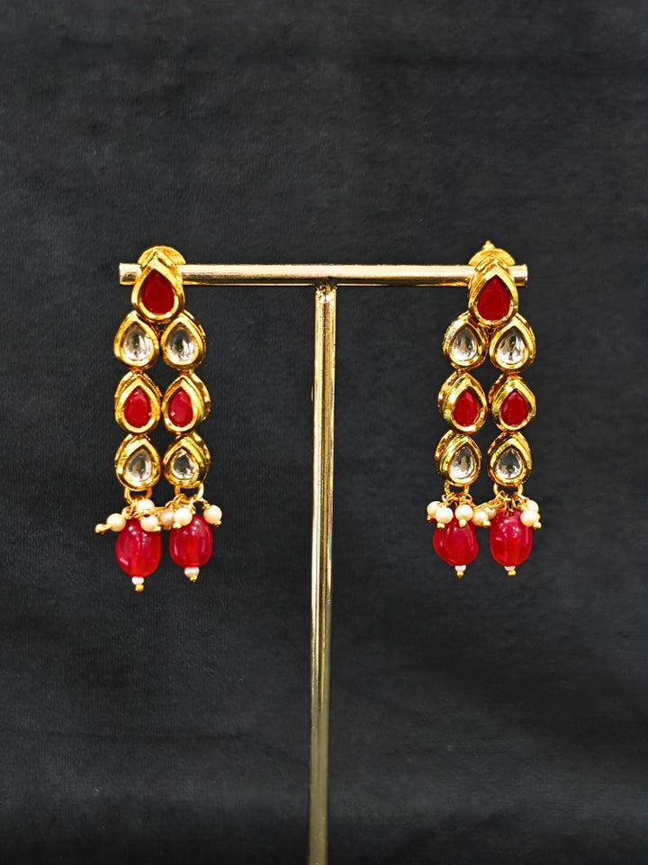 Close-up of an ornate traditional (Gold Polish) Red Kundan jewellery set and earrings with Kundan and Red Colored Stones. Mehendi ceremony look completed with a handcrafted Kundan jewelry set. Royal bridal look featuring a traditional Kundan necklace set.