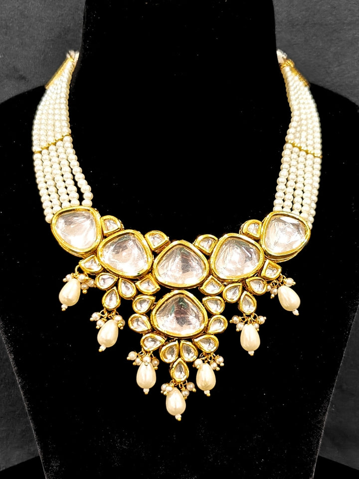 Close-up of an ornate traditional (Gold Polish) White Kundan Collar jewellery set and earrings and maangtikka with Pearls and Kundan. Wedding celebration look enhanced with a Kundan necklace. Mehendi ceremony look completed with a handcrafted Kundan jewelry set. Festive saree styling with a premium artificial Kundan necklace.