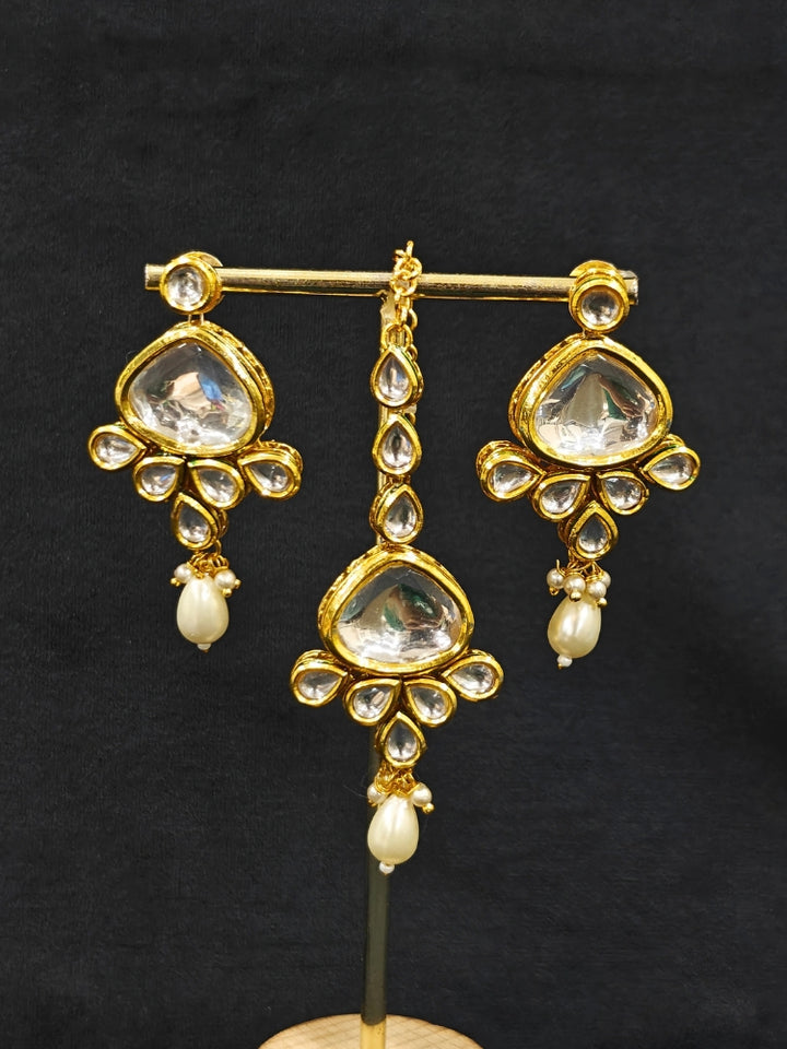 Close-up of an ornate traditional (Gold Polish) White Kundan Collar jewellery set and earrings and maangtikka with Pearls and Kundan. Wedding celebration look enhanced with a Kundan necklace. Mehendi ceremony look completed with a handcrafted Kundan jewelry set. Festive saree styling with a premium artificial Kundan necklace.