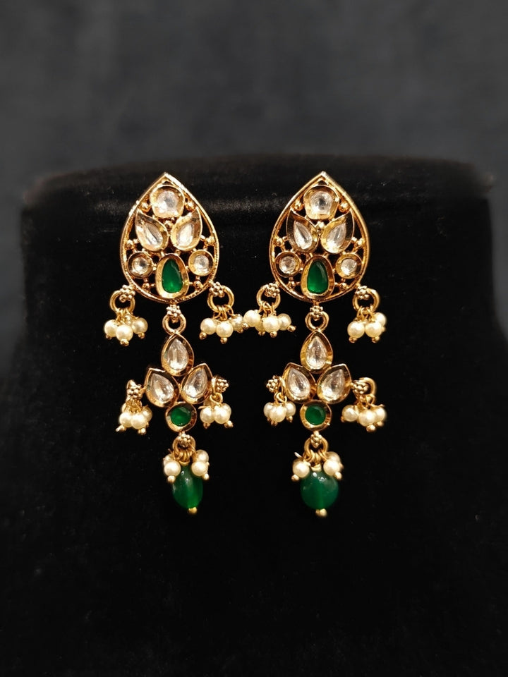 Close-up of an ornate traditional (Gold Polish) Green Collar jewellery set and earrings and maangtikka with Polki, Green Colored Stones, Tumble Beads and Pearls. Woman wearing trending Polki artificial jewelry for the wedding season in India. Woman wearing a lightweight Polki jewelry set for long wedding functions.