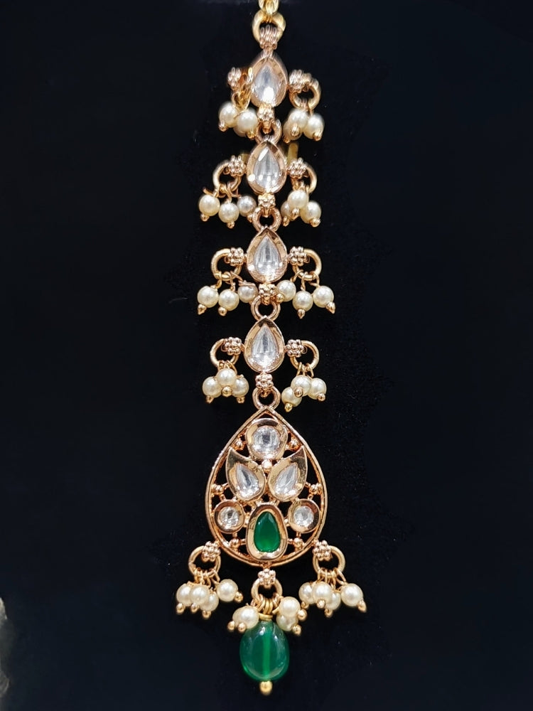 Close-up of an ornate traditional (Gold Polish) Green Collar jewellery set and earrings and maangtikka with Polki, Green Colored Stones, Tumble Beads and Pearls. Woman wearing trending Polki artificial jewelry for the wedding season in India. Woman wearing a lightweight Polki jewelry set for long wedding functions.
