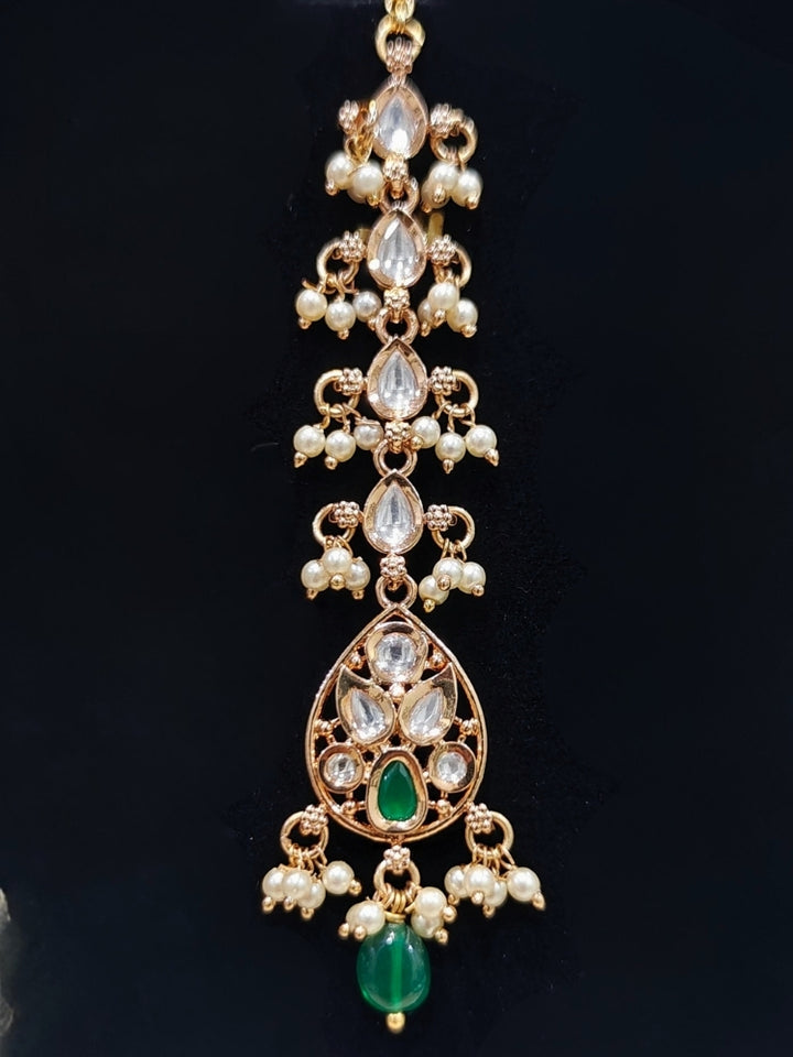 Close-up of an ornate traditional (Gold Polish) Green Collar jewellery set and earrings and maangtikka with Polki, Green Colored Stones, Tumble Beads and Pearls. Woman wearing trending Polki artificial jewelry for the wedding season in India. Woman wearing a lightweight Polki jewelry set for long wedding functions.