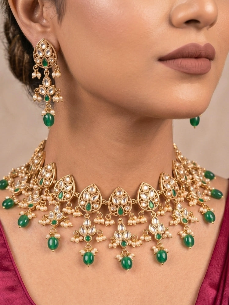 Close-up of a woman wearing an ornate traditional (Gold Polish) Green Collar jewellery set and earrings and maangtikka with Polki, Green Colored Stones, Tumble Beads and Pearls. Woman wearing trending Polki artificial jewelry for the wedding season in India. Woman wearing a lightweight Polki jewelry set for long wedding functions.