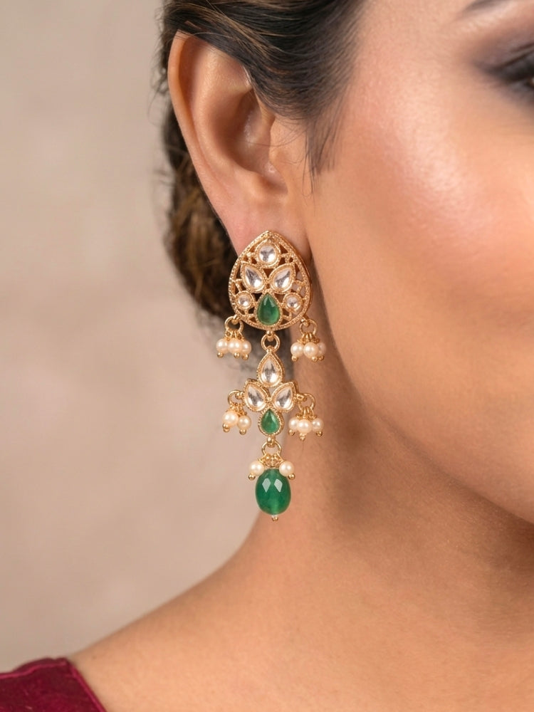 Close-up of a woman wearing an ornate traditional (Gold Polish) Green Collar jewellery set and earrings and maangtikka with Polki, Green Colored Stones, Tumble Beads and Pearls. Woman wearing trending Polki artificial jewelry for the wedding season in India. Woman wearing a lightweight Polki jewelry set for long wedding functions.