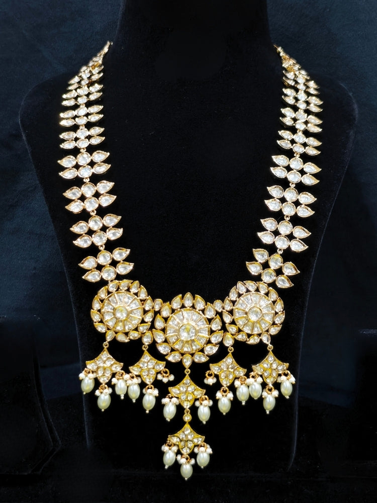 Close-up of an ornate traditional (Gold Polish) Long jewellery set and earrings with Polki and Pearls. Festive saree look completed with a Long Polki artificial jewelry set. Woman wearing trending Polki artificial jewelry for the wedding season in India.