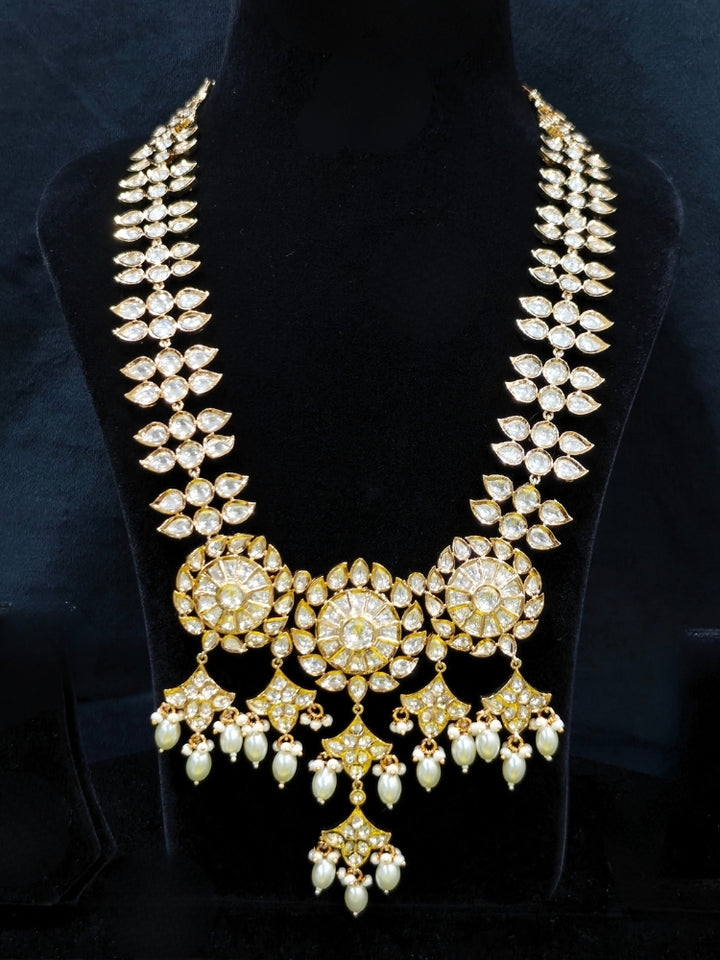 Close-up of an ornate traditional (Gold Polish) Long jewellery set and earrings with Polki and Pearls. Festive saree look completed with a Long Polki artificial jewelry set. Woman wearing trending Polki artificial jewelry for the wedding season in India.
