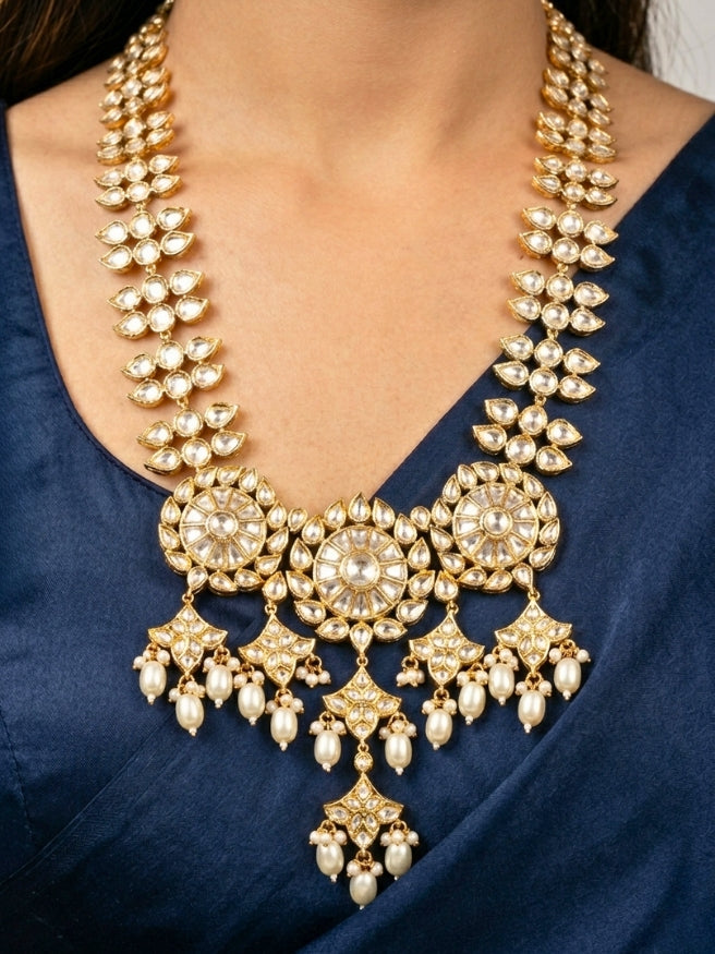 Close-up of a woman wearing an ornate traditional (Gold Polish) Long jewellery set and earrings with Polki and Pearls. Festive saree look completed with a Long Polki artificial jewelry set. Woman wearing trending Polki artificial jewelry for the wedding season in India.