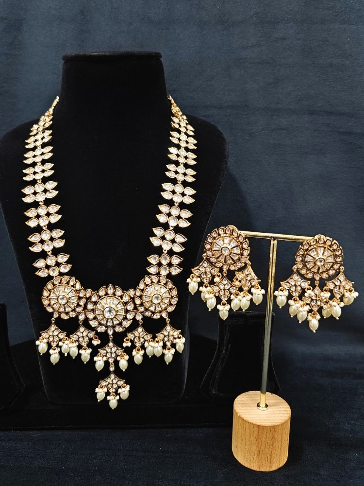 Close-up of an ornate traditional (Gold Polish) Long jewellery set and earrings with Polki and Pearls. Festive saree look completed with a Long Polki artificial jewelry set. Woman wearing trending Polki artificial jewelry for the wedding season in India.
