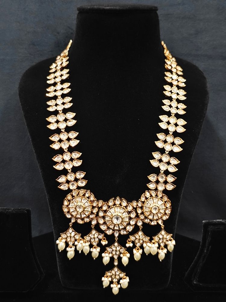 Close-up of an ornate traditional (Gold Polish) Long jewellery set and earrings with Polki and Pearls. Festive saree look completed with a Long Polki artificial jewelry set. Woman wearing trending Polki artificial jewelry for the wedding season in India.