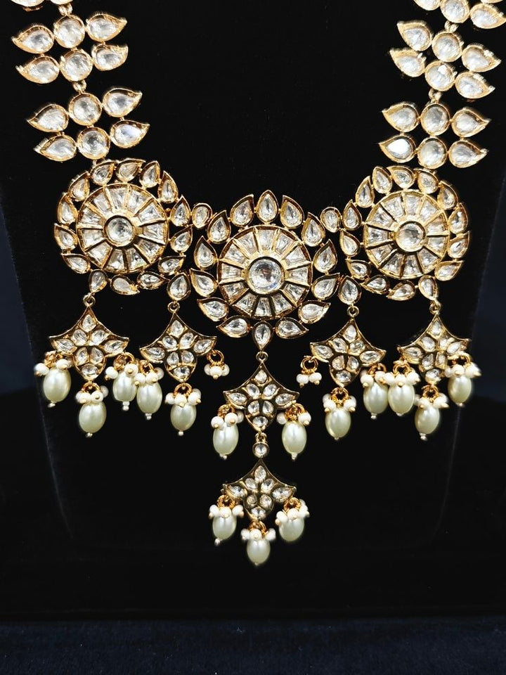 Close-up of an ornate traditional (Gold Polish) Long jewellery set and earrings with Polki and Pearls. Festive saree look completed with a Long Polki artificial jewelry set. Woman wearing trending Polki artificial jewelry for the wedding season in India.