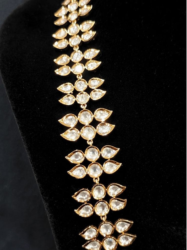 Close-up of an ornate traditional (Gold Polish) Long jewellery set and earrings with Polki and Pearls. Festive saree look completed with a Long Polki artificial jewelry set. Woman wearing trending Polki artificial jewelry for the wedding season in India.