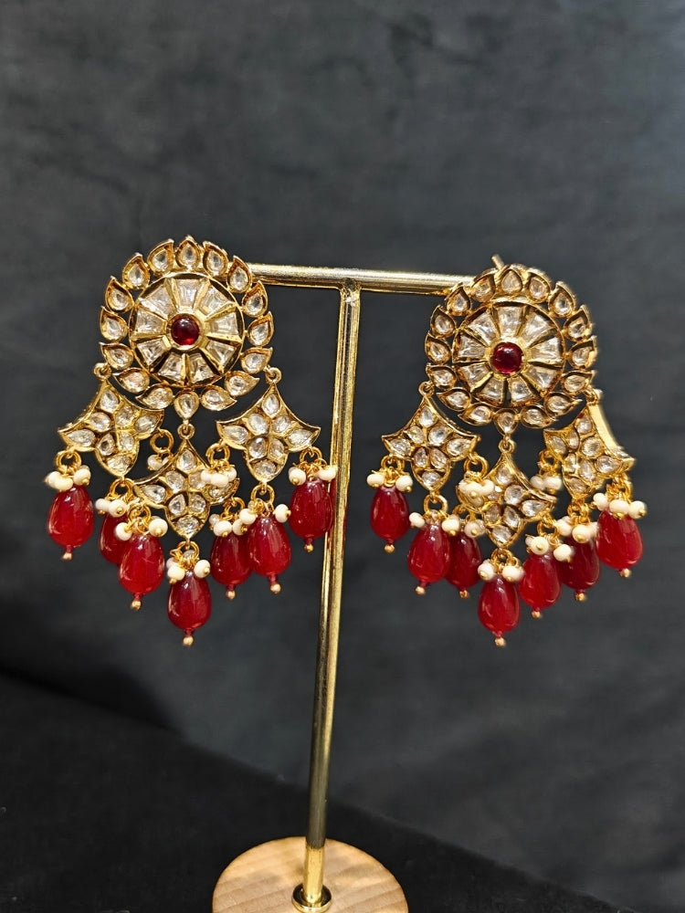Close-up of an ornate traditional (Gold Polish) Ruby Red Long jewellery set and earrings with Polki, Colored Stone and Red Tumble Beads. Festive saree look completed with a Long Polki artificial jewelry set. Woman wearing trending Polki artificial jewelry for the wedding season in India.