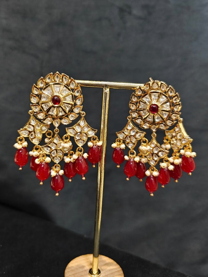 Close-up of an ornate traditional (Gold Polish) Ruby Red Long jewellery set and earrings with Polki, Colored Stone and Red Tumble Beads. Festive saree look completed with a Long Polki artificial jewelry set. Woman wearing trending Polki artificial jewelry for the wedding season in India.
