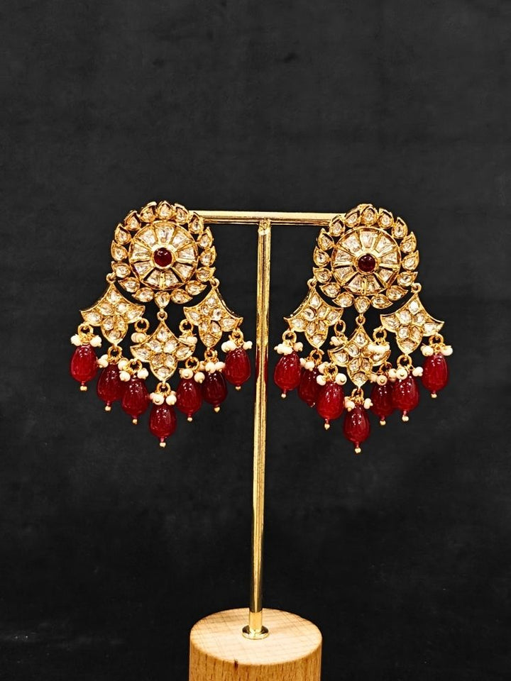Close-up of an ornate traditional (Gold Polish) Ruby Red Long jewellery set and earrings with Polki, Colored Stone and Red Tumble Beads. Festive saree look completed with a Long Polki artificial jewelry set. Woman wearing trending Polki artificial jewelry for the wedding season in India.