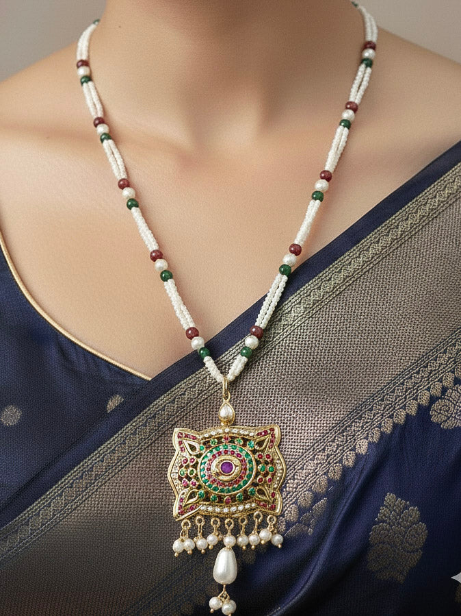 Close-up of a woman wearing an ornate traditional Multi-color jadau gold Pendant set and jadau earrings with pearls, Beads and Color Stone. Elegant look featuring a luxury Jadau artificial Pendant set. Festive saree look completed with a handcrafted Jadau Pendant.