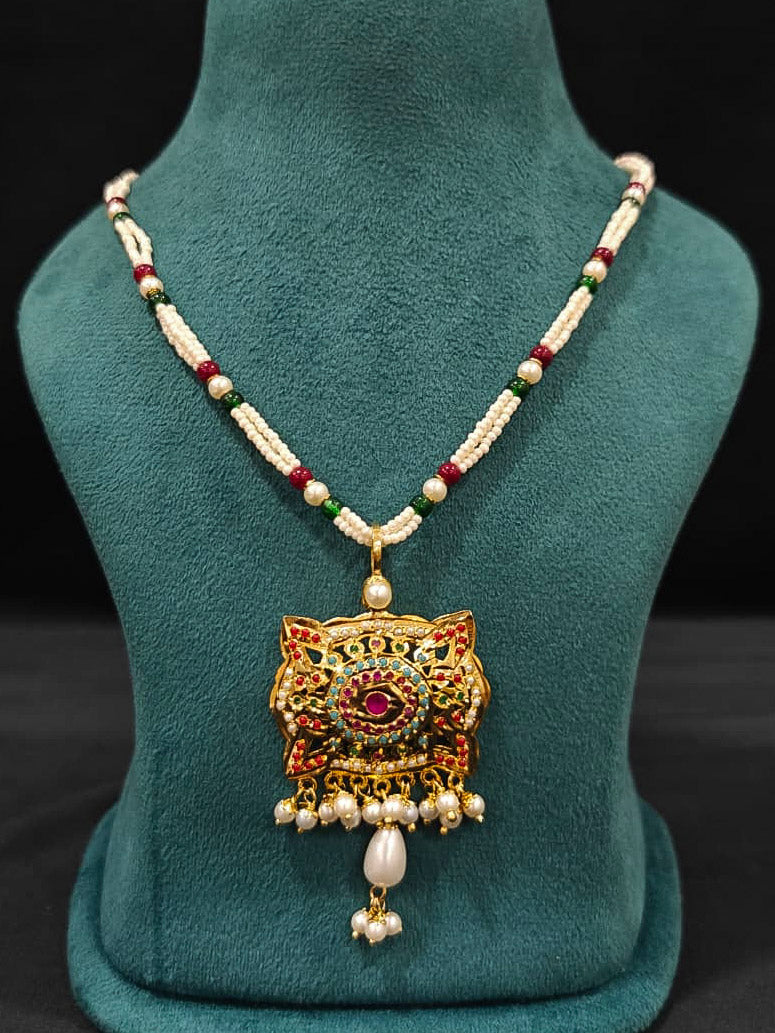Close-up of an ornate traditional Multi-color jadau gold Pendant set and jadau earrings with pearls, Beads and Color Stone. Elegant look featuring a luxury Jadau artificial Pendant set. Festive look completed with a handcrafted Jadau Pendant.