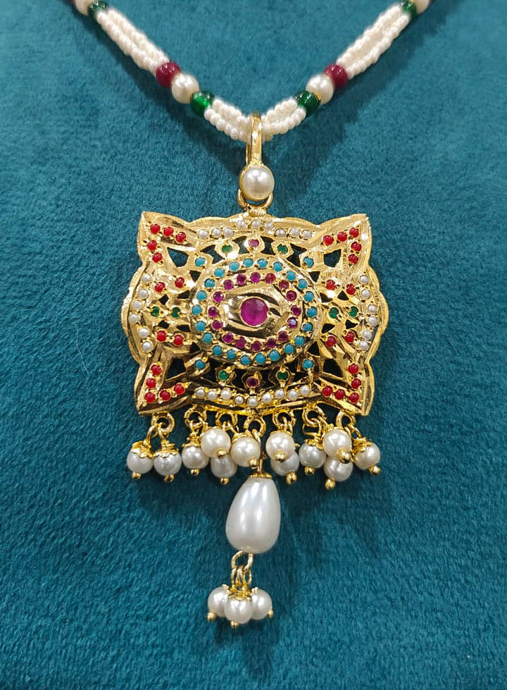 Close-up of an ornate traditional Multi-color jadau gold Pendant set and jadau earrings with pearls, Beads and Color Stone. Elegant look featuring a luxury Jadau artificial Pendant set. Festive look completed with a handcrafted Jadau Pendant.