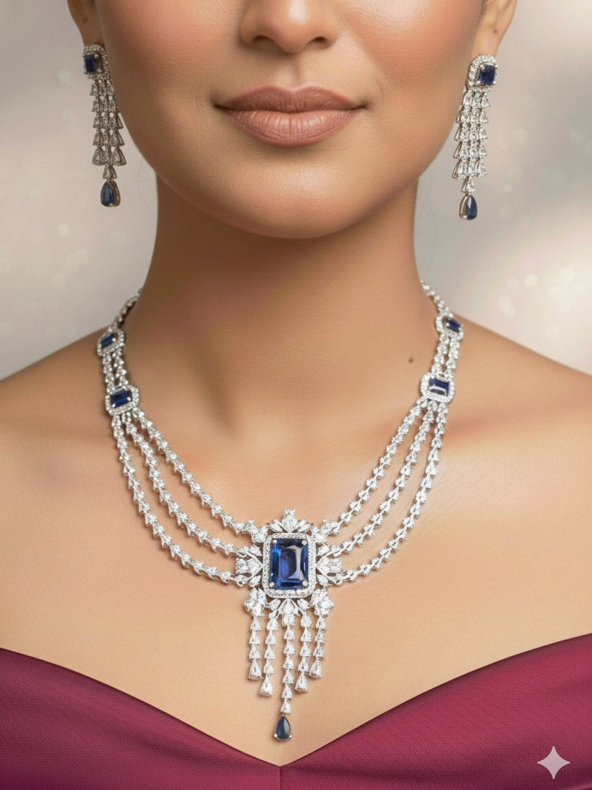 "A stunning woman wearing a glamorous artificial diamond necklace with navy blue colored stone paired with chic earrings and maangtikka, perfect for bridal wear. This high-quality artificial diamond jewelry set is the ideal choice for modern brides looking for a budget-friendly option with timeless sparkle."
