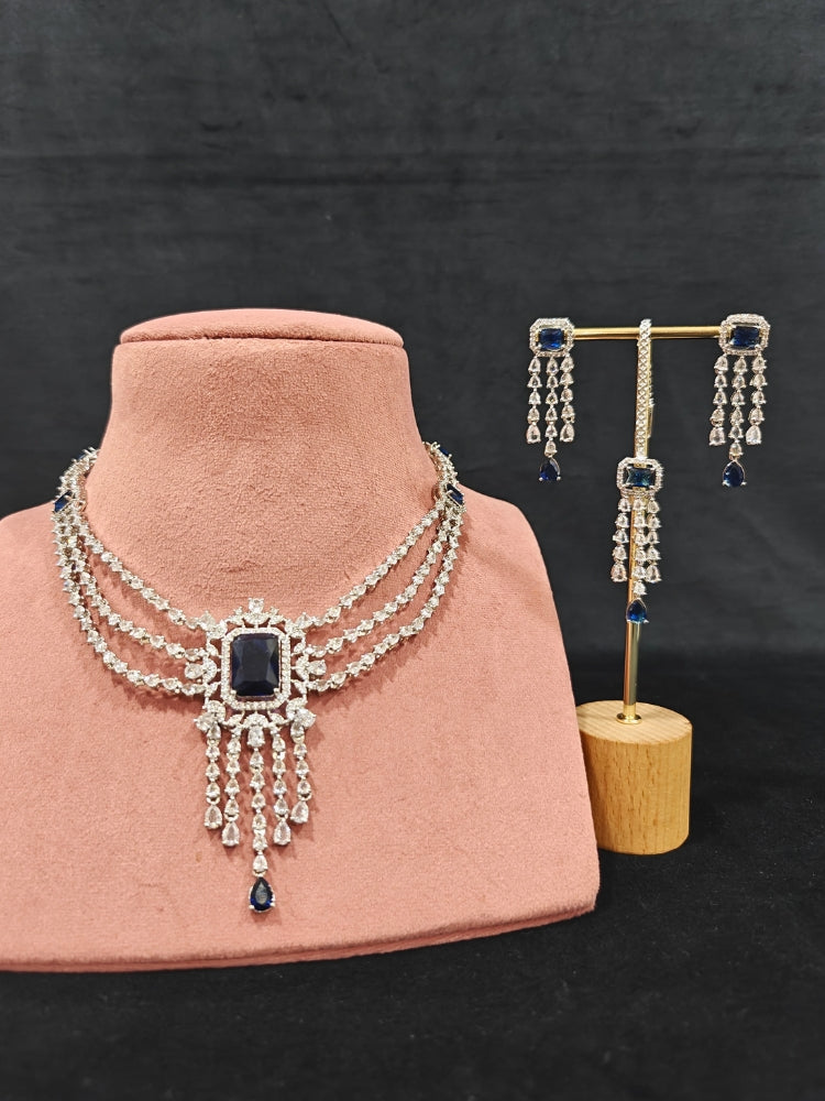 Close-up of an ornate Indo-western Navy Blue Diamond Silver Collar jewellery set and earrings and maangtikka with American Diamond & Colored Stones. Close-up shot of a high-quality American diamond artificial necklace worn for festive celebrations. A sparkling American diamond necklace for reception night.