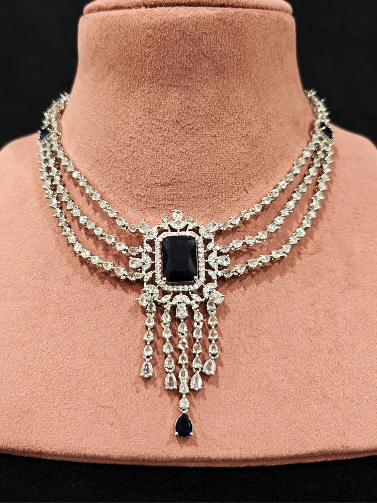 Close-up of an ornate Indo-western Navy Blue Diamond Silver Collar jewellery set and earrings and maangtikka with American Diamond & Colored Stones. Close-up shot of a high-quality American diamond artificial necklace worn for festive celebrations. A sparkling American diamond necklace for reception night.