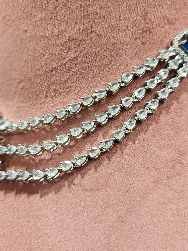 Close-up of an ornate Indo-western Navy Blue Diamond Silver Collar jewellery set and earrings and maangtikka with American Diamond & Colored Stones. Close-up shot of a high-quality American diamond artificial necklace worn for festive celebrations. A sparkling American diamond necklace for reception night.