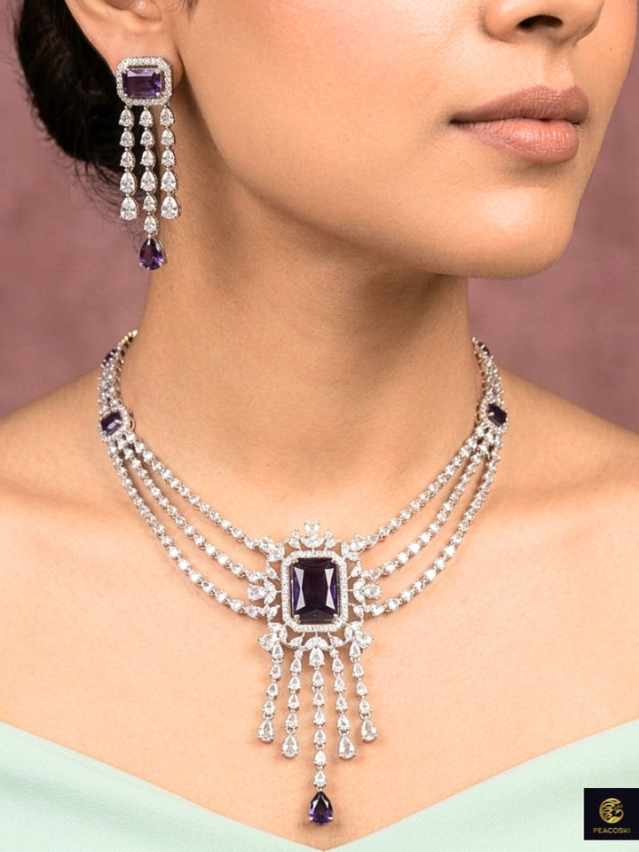 Close-up of a woman wearing an ornate Indo-western Purple Diamond Silver Collar jewellery set and earrings and maangtikka with American Diamond & Colored Stones. Close-up shot of a high-quality American diamond artificial necklace worn for festive celebrations. Bride wearing a sparkling American diamond necklace for her reception night.