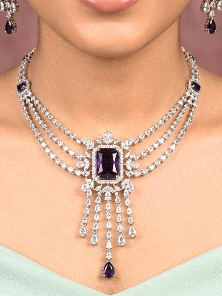 Close-up of a woman wearing an ornate Indo-western Purple Diamond Silver Collar jewellery set and earrings and maangtikka with American Diamond & Colored Stones. Close-up shot of a high-quality American diamond artificial necklace worn for festive celebrations. Bride wearing a sparkling American diamond necklace for her reception night.