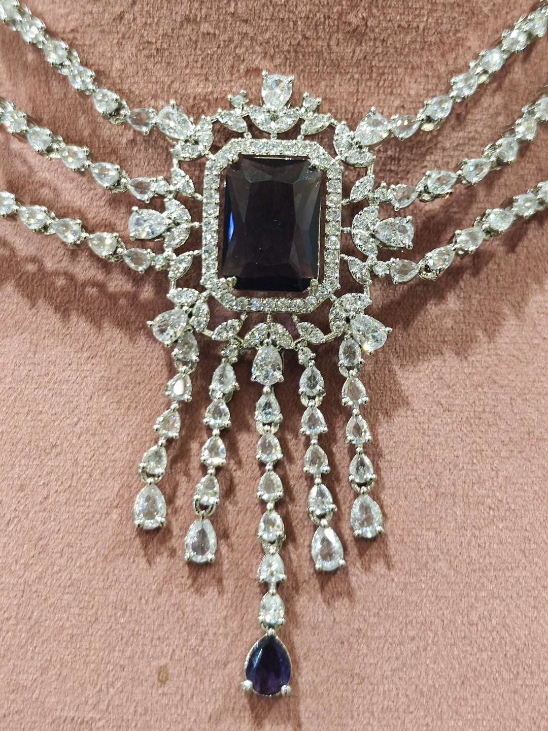Close-up of an ornate Indo-western Purple Diamond Silver Collar jewellery set and earrings and maangtikka with American Diamond & Colored Stones. Close-up shot of a high-quality American diamond artificial necklace worn for festive celebrations. A sparkling American diamond necklace for reception night.