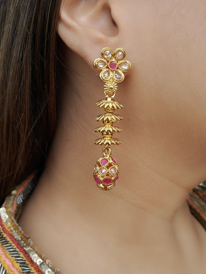 A close-up of a womans ear wearing Laxmi Red Earrings featuring a floral design with dangling gold elements and Red gemstone accents at the oval drop at the bottom —ideal for wedding ceremony jewelry.