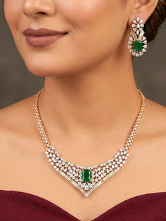 Close-up of a woman wearing an ornate Western (Silver Polish) Green Collar jewellery set and earrings with Green Colored Stone and American Diamond. Woman styling a statement American diamond necklace with an off-shoulder gown for a reception. Party wear outfit completed with a lightweight American diamond necklace.