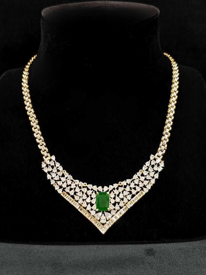 Close-up of an ornate Western (Silver Polish) Green Collar jewellery set and earrings with Green Colored Stone and American Diamond. Woman styling a statement American diamond necklace with an off-shoulder gown for a reception. Party wear outfit completed with a lightweight American diamond necklace.