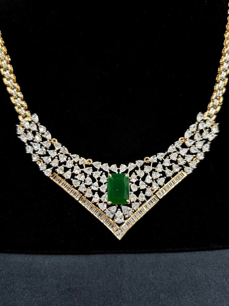 Close-up of an ornate Western (Silver Polish) Green Collar jewellery set and earrings with Green Colored Stone and American Diamond. Woman styling a statement American diamond necklace with an off-shoulder gown for a reception. Party wear outfit completed with a lightweight American diamond necklace.