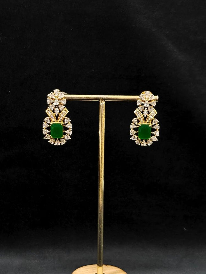 Close-up of an ornate Western (Silver Polish) Green Collar jewellery set and earrings with Green Colored Stone and American Diamond. Woman styling a statement American diamond necklace with an off-shoulder gown for a reception. Party wear outfit completed with a lightweight American diamond necklace.